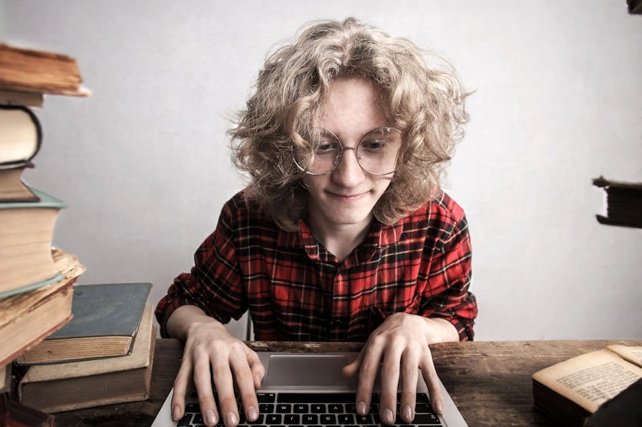 Usměvavý student s notebookem studuje online kurz.